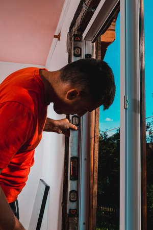 The locksmith-installer after fixing the window checks whether it is fixed to the wall, the installation of the window, the master uses the level. 2020の写真素材