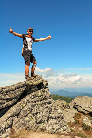A man stands on the edge of a stone on one of the peaks of the Ukrainian Carpathians, the Montenegrin ridge, picturesque mountains on the trampled trails of the Carpathians. 2020の写真素材