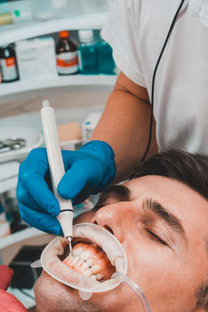 Dental practice, the dentist removes stones and hard plaque from the teeth with the help of...