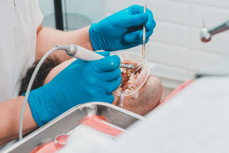 patient removing tartar, the dentist uses ultrasound to remove tartar, dental scaler. 2020