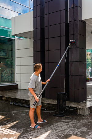 A man washes the wall of the city shopping center. Ivano-Frankivsk, Ukraine July 28, 2020.のeditorial素材
