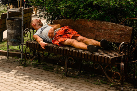 Ivano-Frankivsk, Ukraine July 28, 2020: A homeless man sleeps in a park on a bench in summer. 2020のeditorial素材