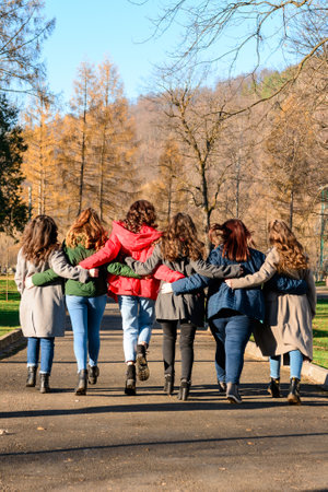 Young group of girls walking in autumn park, autumn clothes and autumn walk. Graduation from high...