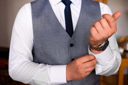 Groom's morning, details and husband's meeting on the wedding day. The man fastens a button on the sleeve of his shirt. 2021の写真素材