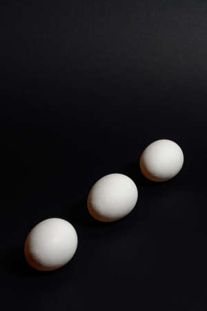 Three white eggs on a black background, dietary and healthy food rich in protein.の写真素材