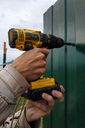 Fastening of a metal sheet to a framework of a fence by means of the screw-driver, screwing of...