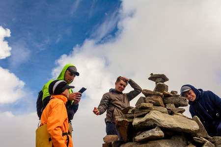 A group of tourists sits on top of the mountain in sportswear, the Montenegrin ridge and the top of...
