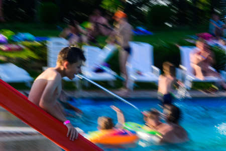 Children's slide in the pool, the visible movement of the descent down the hill, entertainment in the outdoor water park. Motion blur and defocused photo.の写真素材