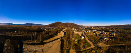 Carpathian village in Ukraine, autumn view of the village, river and mountains from a birds eye...
