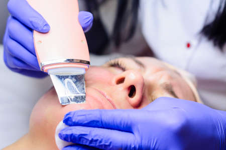 Moisturizing the face and removing keratinized old skin, the beautician uses ultrasound with...