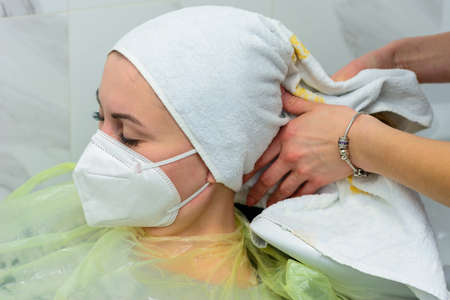 The master wipes the client's head with a white towel. Washing the head in the barbershop, hair...