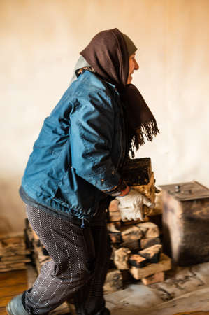 The old woman takes out a brick with soot from the house, Dismantling of the old furnace. newの写真素材