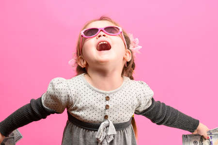 Girl holding paper US dollars, rich and happy child, child and money. newの写真素材