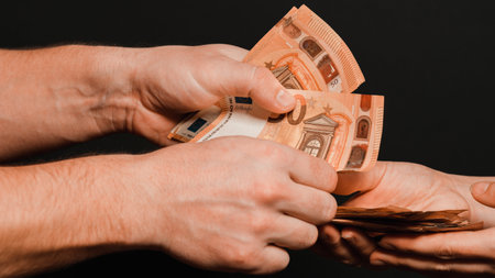 Euro in the hands of a man on a black background, transferring and receiving money as a reward for...