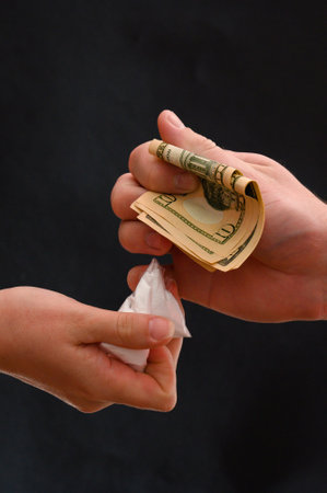 Drug dealer passes a dose to a merchant, sachets of powder on a black background.new