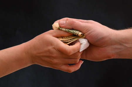 Drug dealer passes a dose to a merchant, sachets of powder on a black background.