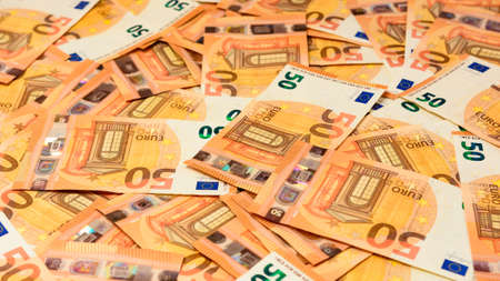 Banknotes in the denomination of 50 euros are scattered randomly on the background, the texture of...