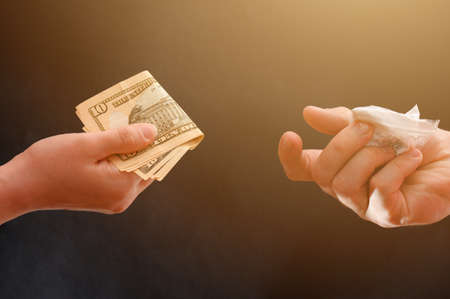 Drug dealer passes a dose to a merchant, sachets of powder on a black background.newの写真素材