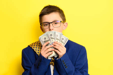 Not a lot of adult child, financially literate boy, money in the hands of a child, portrait on a yellow background. newの写真素材