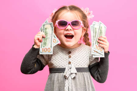 Girl holding paper US dollars, rich and happy child, child and money. newの写真素材