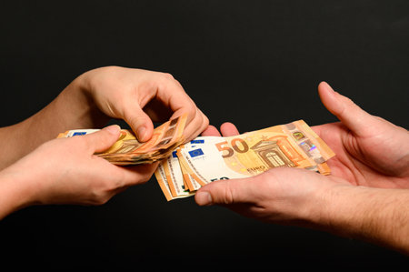 People count money, counting euro bills by man and woman, money on black background.の写真素材