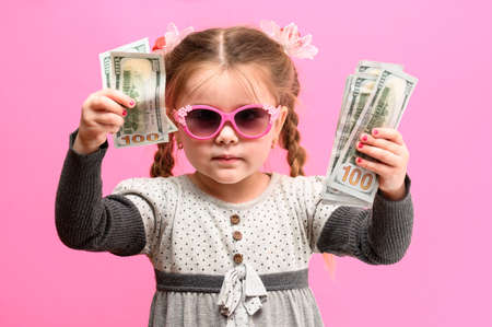 Girl holding paper US dollars, rich and happy child, child and money. newの写真素材
