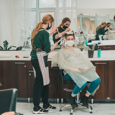 Dolyna, Ivano-Frankivsk March 5, 2021: Pandemic and the work of hairdressers, stylist and client during the procedure of dyeing in medical masks, hair bleaching.のeditorial素材