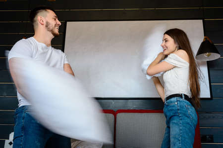 Pillow fight in a hotel room, rest of a young couple, advertising of hotel rooms.