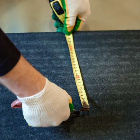 The master prepares bitumen tape for installation, protection of a floor from moisture, measurement and cutting.の写真素材