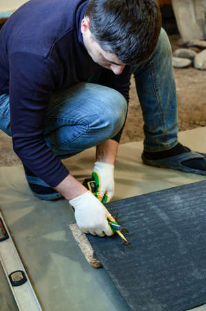 The master prepares bitumen tape for installation, protection of a floor from moisture, measurement and cutting.の写真素材
