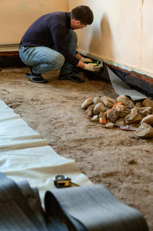 The worker attaches a bitumen tape with a stapler to protect the wood and floor from water, waterproofing and protection.の写真素材