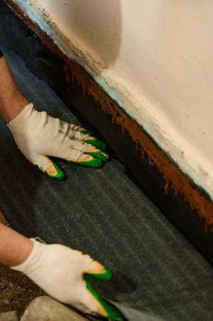 The worker attaches a bitumen tape with a stapler to protect the wood and floor from water, waterproofing and protection.の写真素材
