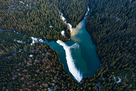 Lake Synevyr in the Carpathians, top view of the lake, mountain lake covered with ice, ice line on...