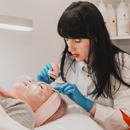 Dolyna, Ukraine March 5, 2021: cosmetologist performs facial cleansing procedure with a scrubber or ultrasonic cleaner, beauty salon.のeditorial素材