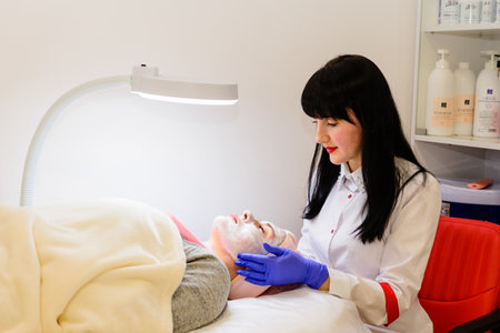 Valley, Ukraine March 5, 2021: facial treatments, applying a white mask on the face, beauty salon in Ukraine.のeditorial素材