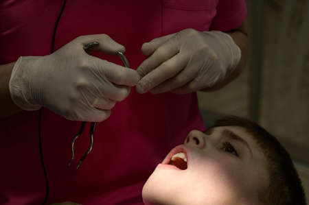 The pediatric dentist treats the child's teeth, the installation of a rubber dam for the child, local light on the patient's face.の写真素材