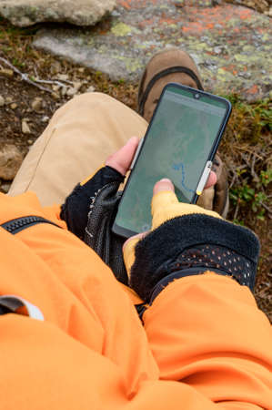 A man travels to the mountains with a smartphone, a blogger in the mountains, a mobile phone in the Carpathians, a navigator in the mountains with a mobile phone.の写真素材