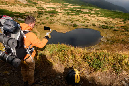 A tourist sits on the grass high in the mountains on the background of Lake Nesamovite, a tourist...