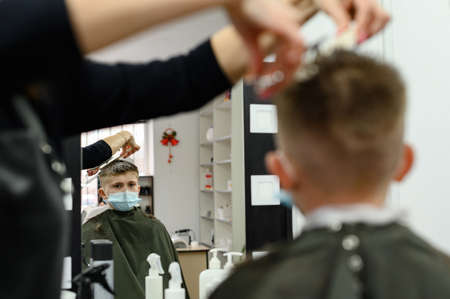 Children's haircut in the barbershop, stylish and modern haircut for schoolchildren, work during the...