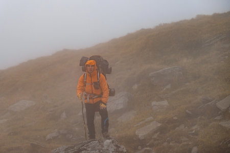 A man with a backpack for a hike climbs to the top of the mountain on a rocky path, a tourist hike...