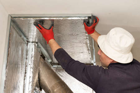 Mineral wool with foil, thermal protection for the wall from the fireplace, installation of metal beacons, screwing the beacons to the wall with a screwdriver, Construction works.の写真素材