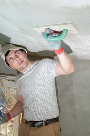 The master rubs the ceiling with a moisture-absorbing grater for lime plaster, repair work himself.