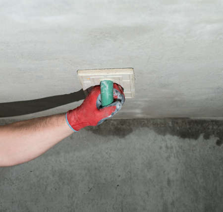 Rubbing fresh lime plaster with a moisture-absorbing sponge to level the wall, construction grater...