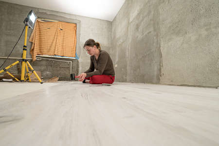 Woman installs quartz vinyl flooring at home, exhausted woman from work, installation of quartz vinyl flooring.の写真素材