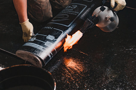 Dolyna, Ukraine March 16, 2022: Installation of waterproofing on the floor, heating the roll with a...