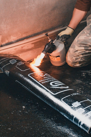 Dolyna, Ukraine March 16, 2022: repair work in the house, installation of waterproofing on the floor, heating the resin and roll with a blowtorch.のeditorial素材