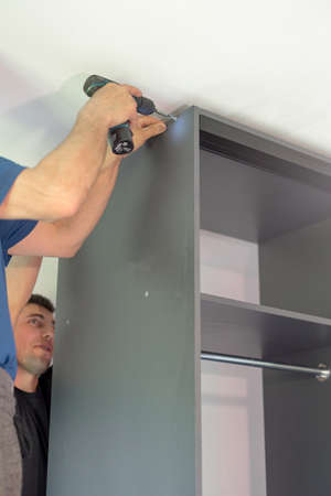 The process of screwing the screw, installing a sliding door wardrobe, components and tools for...