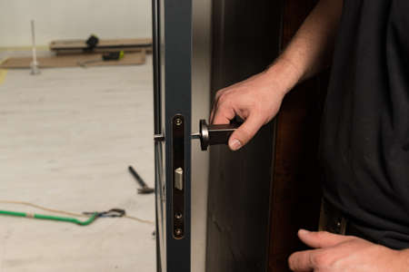 A carpenter installs a metal doorknob for an interior door, installing a door and a doorknob.
