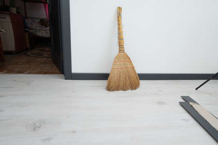 A straw broom on the background of a white wall, an old broom in a room.の写真素材