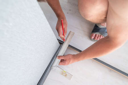 Installing a plinth in the room, measuring the required length using a square and a ruler, notching...